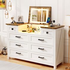 a white dresser with an illuminated mirror on top