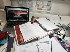 an open book sitting on top of a desk next to a laptop computer and other office supplies