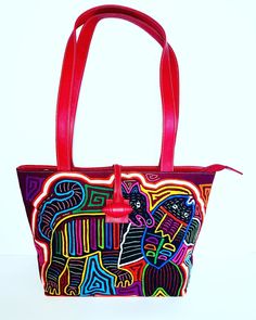 "A red leather shoulder bag with an exquisite and original hand-sewn Mola decoration on the front.  Each Mola design and textile is 100% unique and 100% handmade by Indigenous Kuna woman. Fashionable, timeless, and practical, a perfect bag for any occasion. Features: - Zippered main compartment for safety - Two inset pockets for mobile/tissues - One interior zippered pocket for money/cards/keys Dimensions: W 34cm x H 24cm x D 12cm - Handle drop 29cm Fabric: Made from high quality leather, durabl Traditional Red Shoulder Bag For Everyday Use, Artisan Red Shoulder Bag For Everyday Use, Artisan Red Tote Shoulder Bag, Artisan Red Rectangular Shoulder Bag, Traditional Red Bags With Leather Handles, Artisan Red Bag For Daily Use, Artisan Red Shoulder Bag With Leather Handles, Artisan Red Bags For Daily Use, Red Handmade Satchel Shoulder Bag