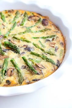 a quiche with asparagus and mushrooms in a white dish