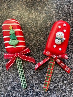 two lollipops decorated with christmas decorations on top of a granite countertop