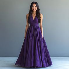 a woman in a long purple dress posing for the camera with her hands on her hips