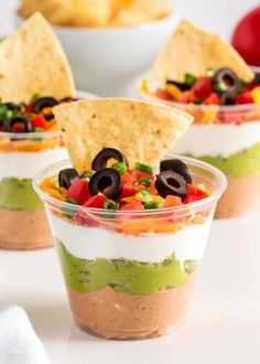 three small cups filled with mexican dips and tortilla chips on the side