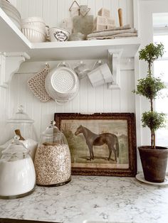 a kitchen counter topped with lots of white dishes and pots on top of it's shelves