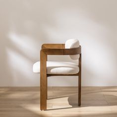 a white chair sitting on top of a hard wood floor in front of a wall