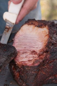 a person cutting up some meat on top of a grill