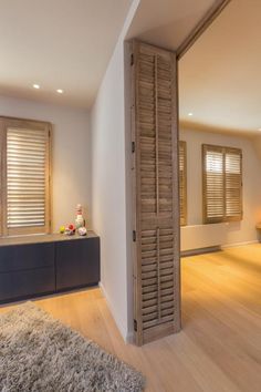 an empty room with wooden shutters and a rug on the floor in front of it