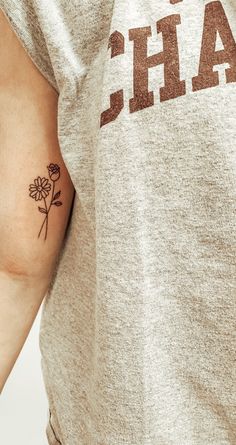 a person with a flower tattoo on their left arm and right arm behind her back