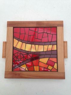 a wooden frame with a stained glass window in it's center on a white wall