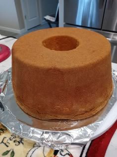 a cake sitting on top of a pan covered in tin foil next to a stove