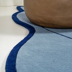 a blue and brown rug on the floor next to a large leather bean bag chair