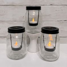 three mason jars with candles in them are sitting on a white counter top next to each other