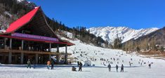 many people are standing in the snow outside of a ski lodge on a sunny day