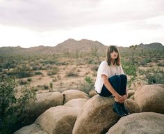 a woman is sitting on some rocks in the desert