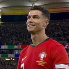 a man in a red shirt is smiling at the camera while standing in front of a crowd