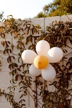 white balloons are attached to the side of a brick wall with vines growing on it