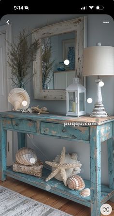 a blue table with shells on it and a mirror in the back ground, next to a lamp