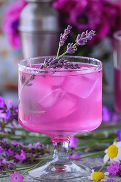 a pink drink with lavender sprigs on the rim and purple flowers in the background