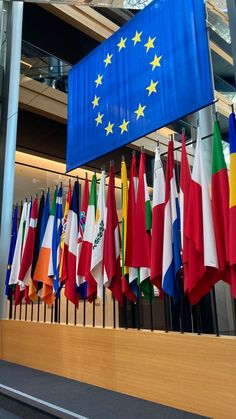 many flags are hanging on the wall in front of a sign that says european union