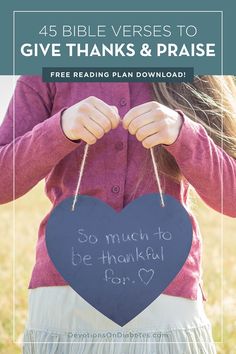 a girl holding a heart shaped sign with the words give thanks and praise written on it