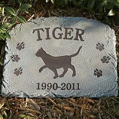 a stone with a dog's name and paw prints on it in the grass