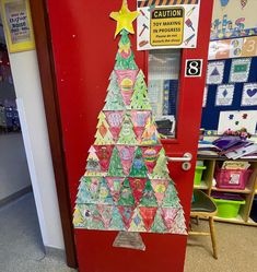 a christmas tree made out of paper sitting on top of a red door in a classroom