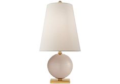 a table lamp with a white shade on the base and a gold frame around it