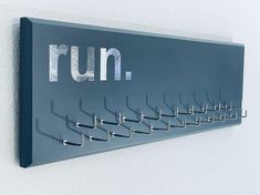 a wall mounted coat rack with metal hooks on it's sides and the word run written in large letters