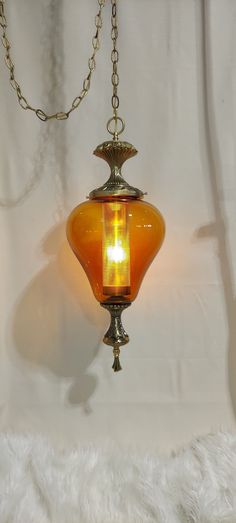 an orange glass light hanging from a chain