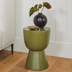 a vase sitting on top of a green table next to a black ball and brush