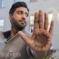 a man is holding his hand up to show the hendi tattoo design on it