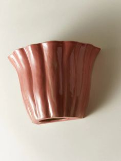 a pink vase sitting on top of a white wall