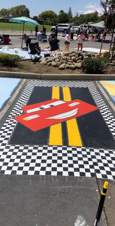 an artistic painted parking lot in the middle of a park with people walking around it