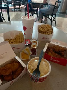 some chicken and waffles are sitting on a table with two cups of ice cream