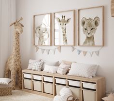 a nursery room with three pictures on the wall and two stuffed animals hanging above it