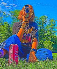 a person sitting in the grass with a camera on their head and some cans behind them