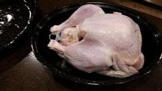 a whole chicken in a black bowl on the counter