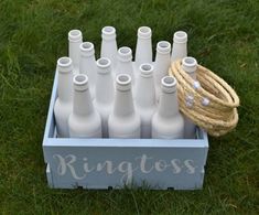 a bunch of bottles that are in a box on the grass with some rope around them