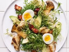 a white plate topped with meat and veggies next to an egg on top of lettuce