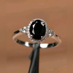 a black and white diamond ring sitting on top of a wooden stand in front of a brown background