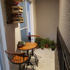 two wooden chairs sitting at a small table on the side of a building next to a window