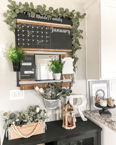 a black table topped with potted plants next to a chalkboard and calendar on the wall