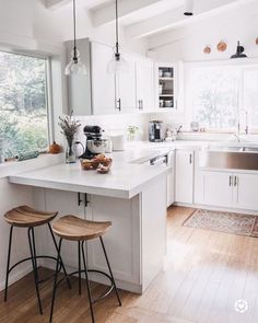 a kitchen with white cabinets and wooden stools