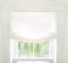 a cat sitting on the window sill in front of a white curtained window