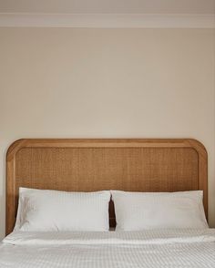 a bed with white sheets and pillows in a room