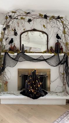 a fireplace decorated for halloween with branches and lights in the mantel, along with a mirror above it