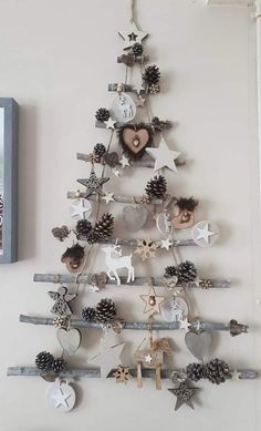 a christmas tree made out of wooden branches and ornaments hanging on the wall next to a framed photo