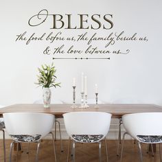 a dining room table with four chairs and a wall decal that says, blessing