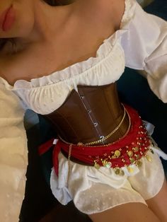 a woman wearing a corset with red and gold beads