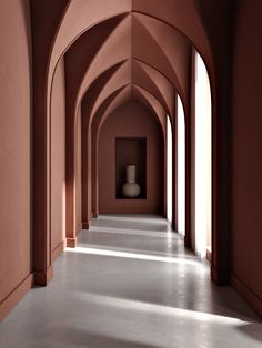 an empty hallway with pink walls and arches